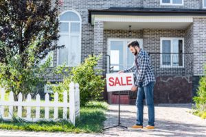 young man with sale board selling his house. A post about the selling your house privately process.
